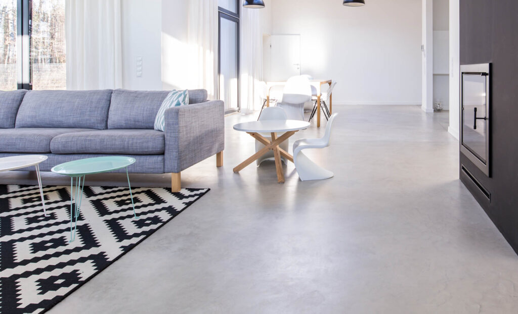modern living space with polished screed floor, L shape sofa, chairs and table