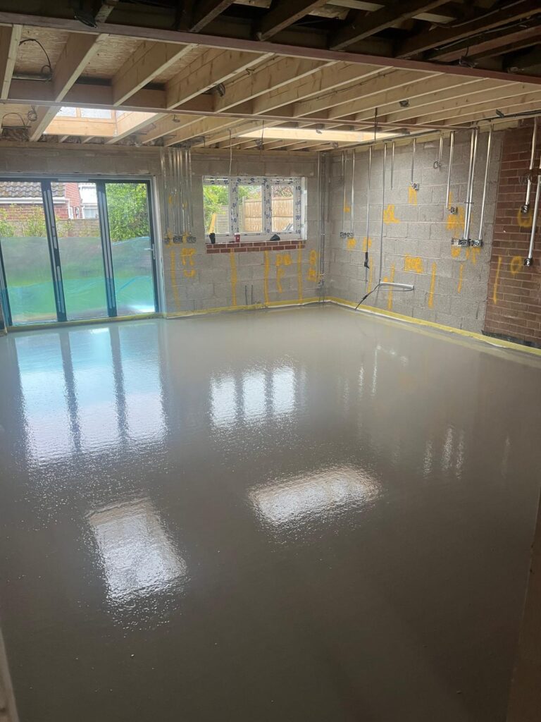 Wet liquid flow screed floor in the empty kitchen area of a home renovation