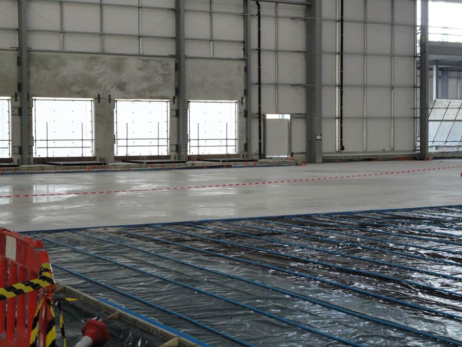 Large floor area in commercial building with underfloor heating pipes installed and liquid flow screed laid over part of the floor