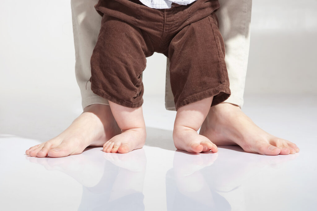 Adult's and baby's feet shown standing on a polished screed floor in their home.